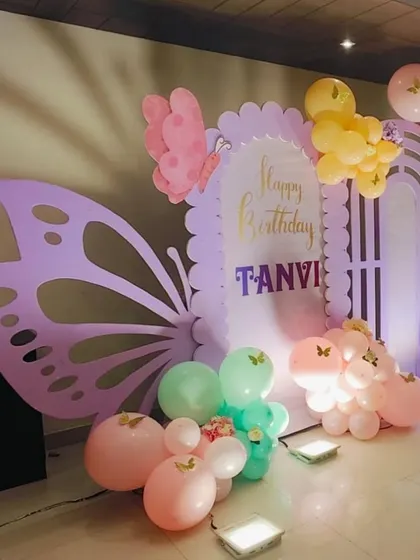 A close-up on the large lavender butterfly wing prop and pastel balloon clusters.