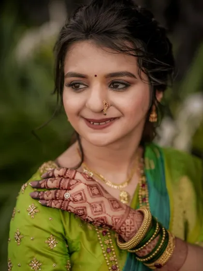 A close-up of the bride, highlighting her intricate henna design and the delicate details of her green saree.