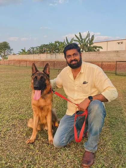 A proud owner with his handsome German Shepherd, enjoying a day out at the park.