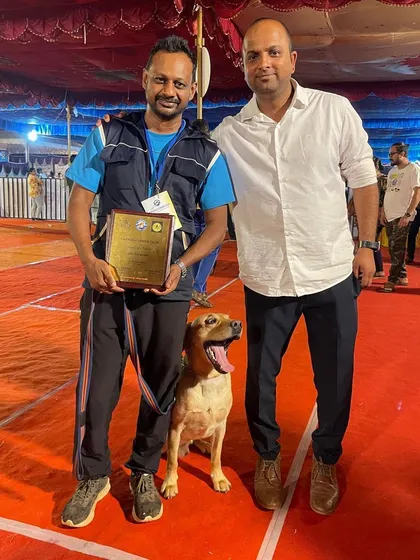 A trainer and handler posing with their winning dog.