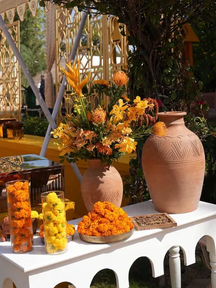 Details of the Haldi decor, including terracotta vases, brass elements, and an abundance of fresh marigolds.