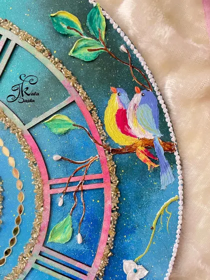 A close-up of the colorful birds painted on the galaxy-themed clock, nestled among the branches.