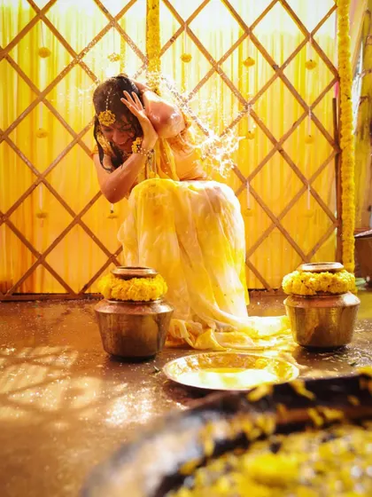 A candid shot of the bride enjoying the water-pouring ritual during her Haldi ceremony.