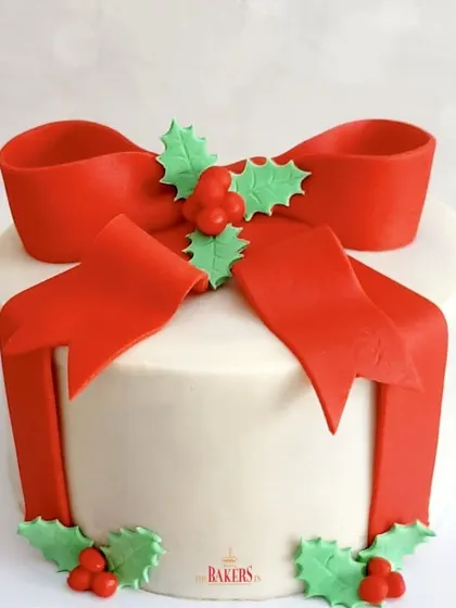 Wishing you a Merry Christmas with this classic gift box cake. The bright red bow and holly leaves are handcrafted from fondant, while the cake itself is a delicious, moist bake.