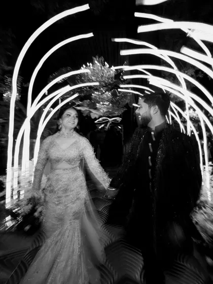 A creative, motion-blur shot of the couple walking through a tunnel of lights at their Sangeet or Cocktail party, captured in black and white.
