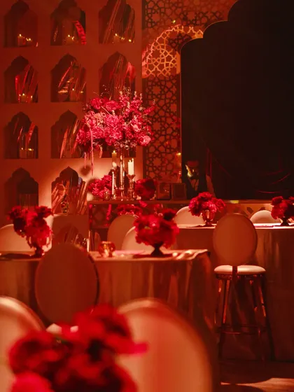 The dining tables were dressed in gold, with towering arrangements of red flowers, creating an intimate yet opulent dining experience.