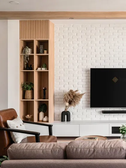 A close-up of the TV unit, showing the combination of a white brick wall, a floating console, and a custom wooden display cabinet. The leather armchair adds a classic, comfortable touch.