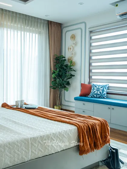 This image highlights the cozy window bench with built-in storage, upholstered in a bold blue fabric. It's a perfect reading nook, complemented by decorative wall molding and modern art.