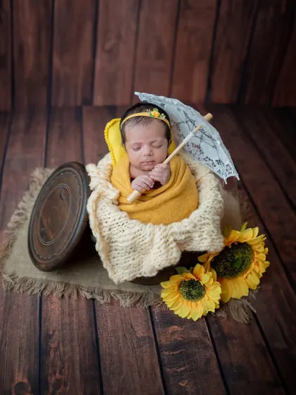 A wider view of the sunflower-themed setup, showing the baby in a rustic wooden box with a vintage feel.