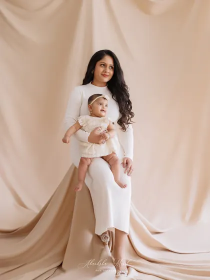 A serene and elegant portrait of a mother and her baby. The neutral tones of their outfits and the backdrop create a calm, sophisticated, and timeless feel.