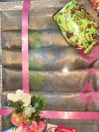 A set of beautiful pastel-colored sarees packed with a contrasting green potli bag.