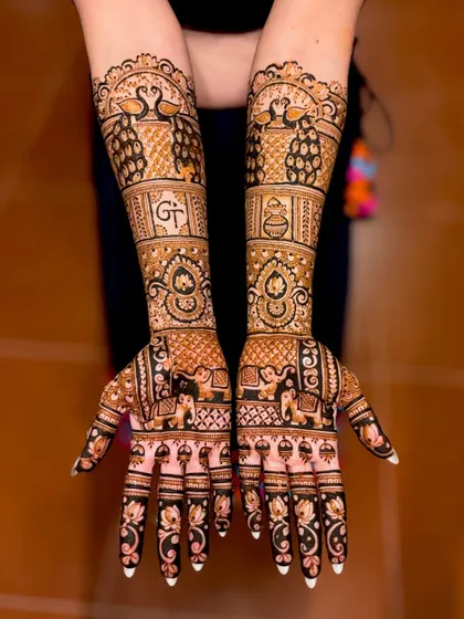 A personalized bridal mehendi featuring the couple's initials, "GT," and various traditional symbols.