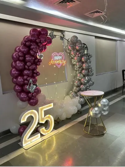 This shot captures the full 25th-anniversary setup, including the light-up numbers, balloon arch, and a small table for the cake.