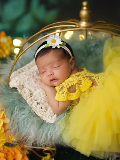 A close-up of the baby in her yellow tulle dress, wearing a sweet daisy headband for her sunny-themed photoshoot.