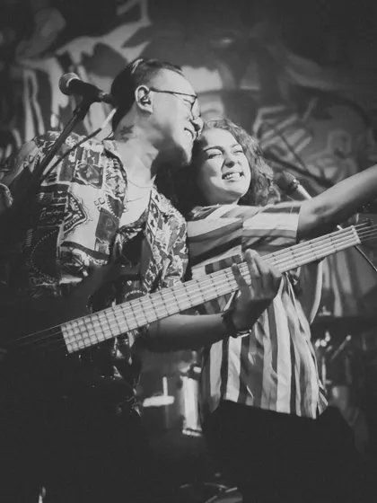 A black and white shot capturing a moment of pure joy between Johaan and Dhruvi on stage. This is the authentic connection that fuels our pop and rock performances.