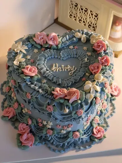 A stunning heart-shaped cake inspired by the enchanting garden from "Howl's Moving Castle," featuring elaborate floral piping in a vintage style.