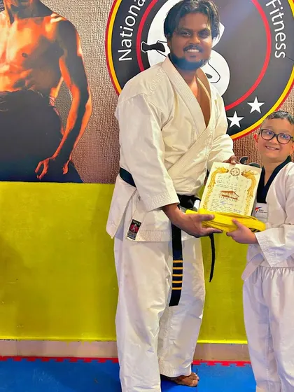 This student is happy to receive his yellow belt certificate, marking his progress in Taekwondo.