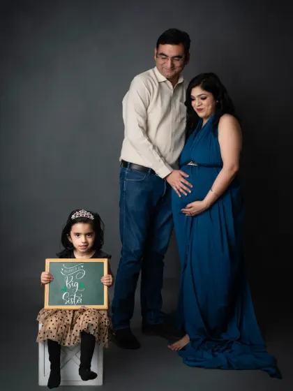 A proud big sister holds a sign announcing her new role in this sweet family maternity session.