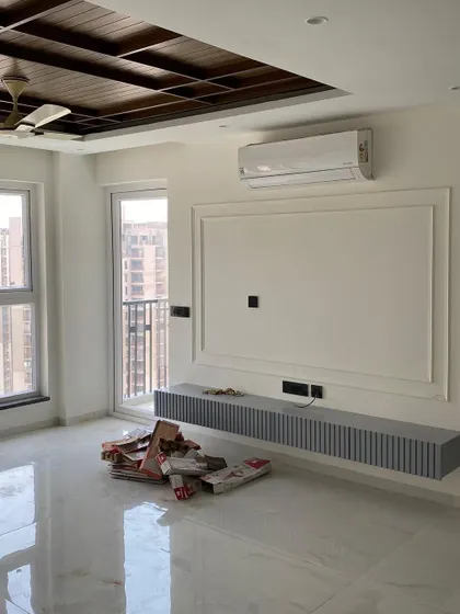 A work-in-progress shot of a living room, showing a newly installed floating TV console with a fluted grey finish.