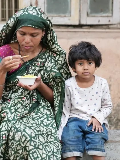 A mother and child share a meal provided by our Annam Brahma initiative. We believe in nourishing both the body and the mind.