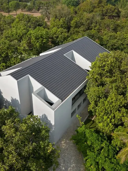 An aerial view of the Mango Orchard House shows how we integrate architecture into the landscape. The monolithic form is carefully positioned within a mature orchard, with the building's layout designed to preserve every existing tree and create a harmonious relationship with nature.