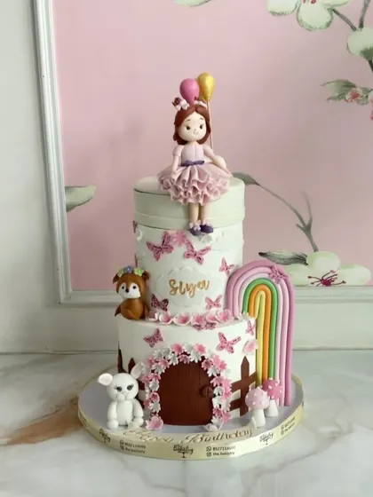 Turning sweet dreams into reality with this two-tiered doll cake for Siya. It features a fairy door, a rainbow, and adorable animal friends.