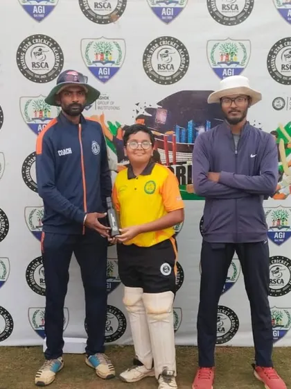 A player receives his award from the coaches, with his teammates applauding in the background.