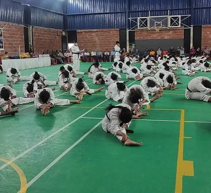 A wide shot of the stretching session during the belt exam, with parents watching from the sidelines.