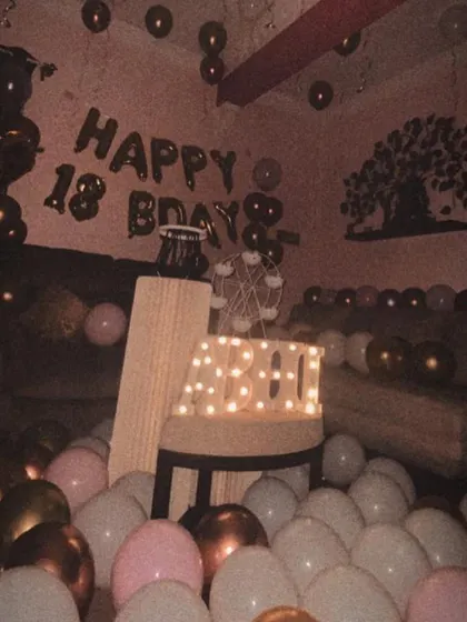 A moody and cool vibe for an 18th birthday. This home decor setup uses pink, white, and metallic balloons covering the floor, with foil balloons on the wall and marquee letters for the name "ABHI".