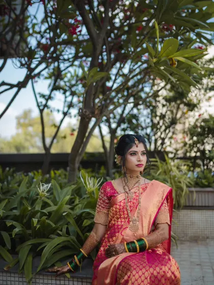 A thoughtful, posed portrait of the bride seated in a garden. The composition and her expression give the photo a serene and regal quality.