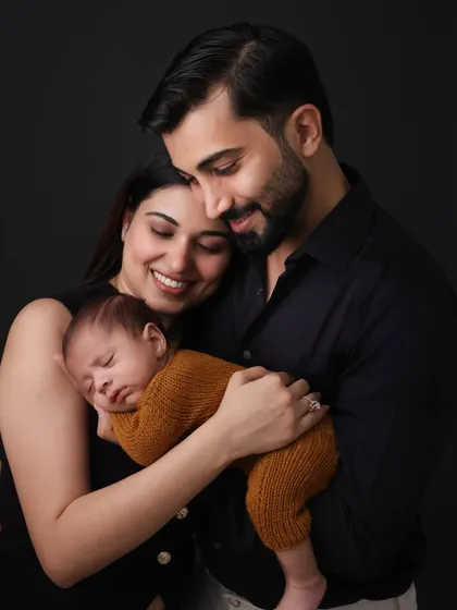 A tender moment with dad holding his newborn close. This portrait, set against a dark, moody backdrop, emphasizes the protective and gentle nature of a father's love.