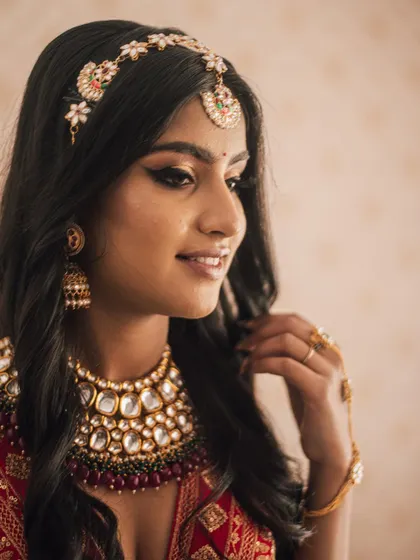 A classic profile shot that highlights the sharp winged eyeliner and the intricate details of her traditional headpiece.