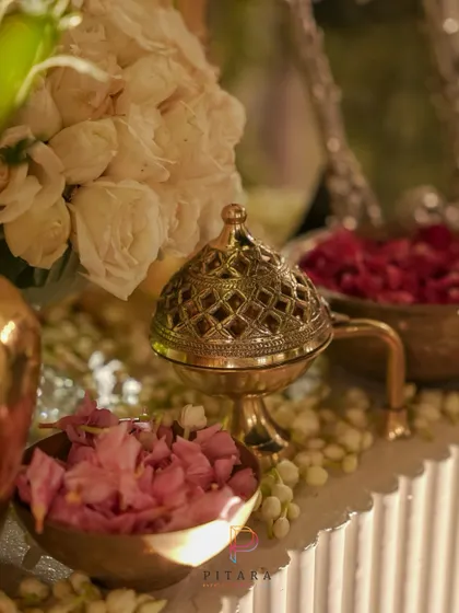 A close-up of a vintage brass incense burner, surrounded by bowls of fresh rose petals and fragrant jasmine. These traditional elements add a sensory layer to the decor, creating a truly immersive experience.