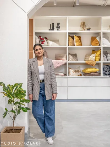 One of our designers, standing near the custom shelving unit she helped create for the FA Home store. This adds a human element, connecting our team to the finished project.