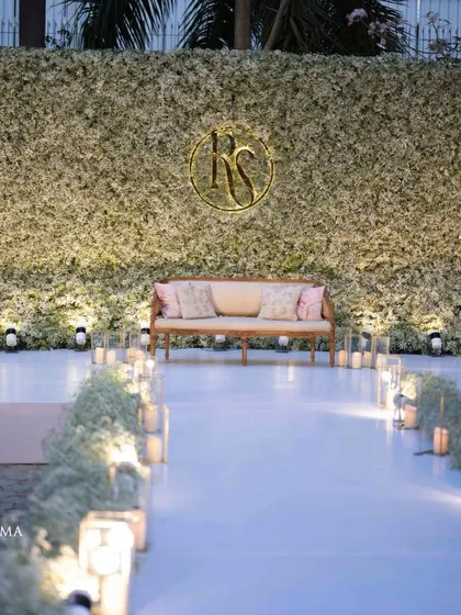 An ethereal all-white reception. The aisle and backdrop are adorned with clouds of baby's breath, while flickering candles cast a warm, romantic glow, creating a scene straight out of a fairy tale.