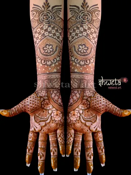 An intricate and dense bridal mehendi design. The pattern is filled with floral motifs, checks, and swirls, creating a rich and luxurious look for the bride's hands.