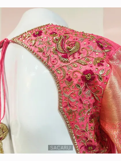 A Kanjeevaram saree blouse with a statement back design. The entire back panel is heavily embroidered with floral and peacock motifs in shades of pink and gold.