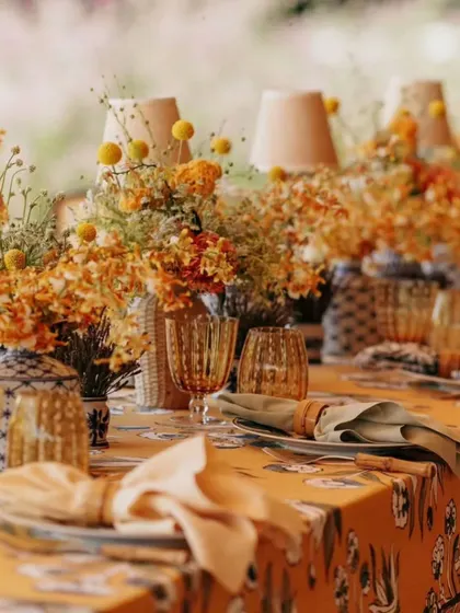Attention to detail is everything. This tablescape from a garden party features a custom floral-print tablecloth, unique glassware, and small table lamps that add a warm, intimate glow to the setting.