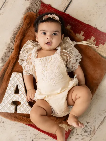 A beautiful, alert expression. This 5-month-old is perfectly framed by her initial and a rustic, textured background.