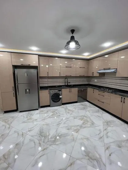 This spacious L-shaped kitchen combines beige cabinetry with black granite countertops for a warm, contemporary look. The design includes ample storage and counter space, with a layout that is perfect for an open-plan home.