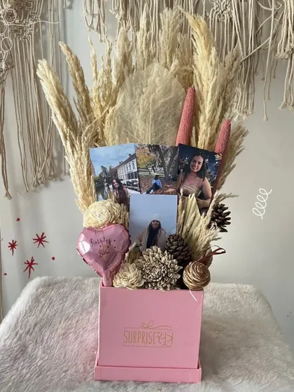A pretty-in-pink birthday bouquet box with dried florals and personal photos, perfect for a friend's special day.