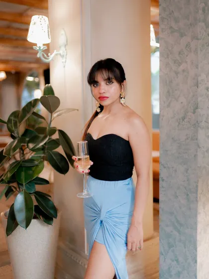 A chic portrait of a model holding a glass of champagne. The elegant indoor setting and her stylish outfit create a sophisticated and celebratory mood.