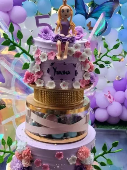 A close-up of a Rapunzel-themed butterfly cake for a 5th birthday. Notice the detailed floral decorations and the personalized name 'Yuvika' on the lavender frosting.