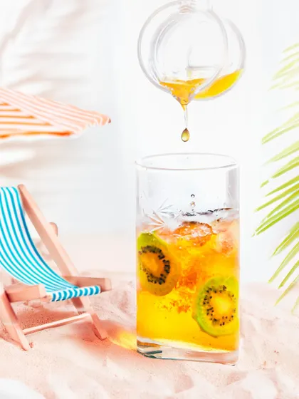A playful and creative shot of kiwi iced tea on a miniature beach setup, complete with sand and a beach chair. This shows my ability to create fun, conceptual product visuals.