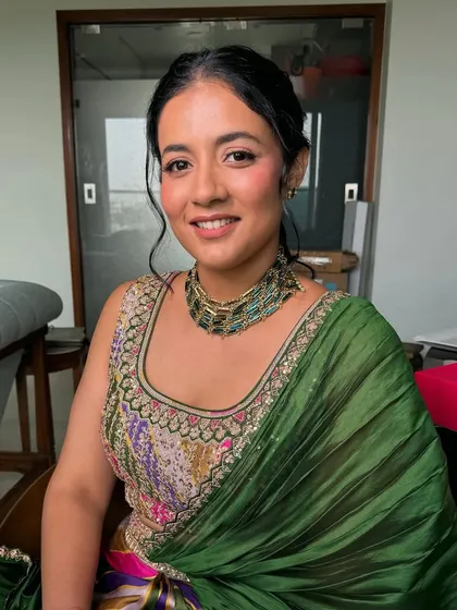 A seated portrait of the bride at her home Mehndi. She looks relaxed and beautiful, with a natural makeup look that enhances her features.