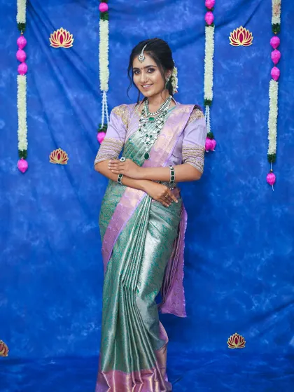 A full-length view of the lavender and green silk saree against a festive blue backdrop. This unique color combination is perfect for a bride who wants to stand out.