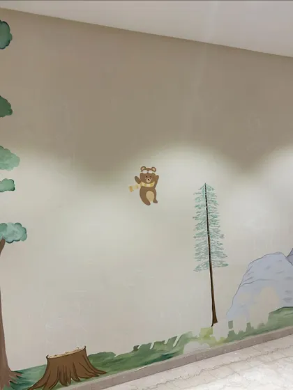 A glimpse of the finished nursery wall, with a happy little bear waving hello. The goal was to create a friendly and calming environment.