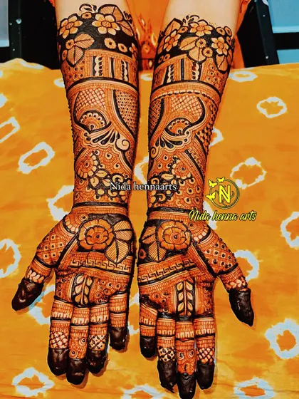 This full coverage Indian bridal design uses bold lines and dark filled areas to create a striking contrast. The floral patterns on the palm and wrist stand out beautifully.