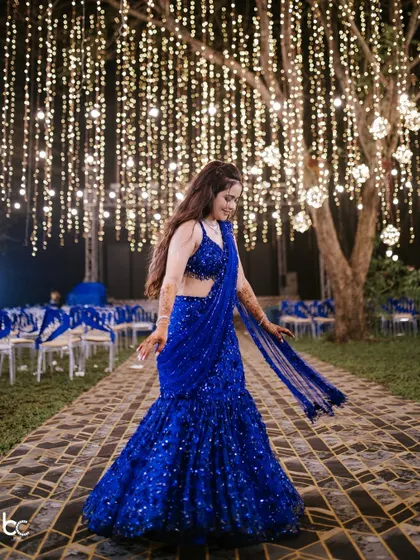 A beautiful full-length shot of the bride in her shimmering blue lehenga, twirling under a canopy of fairy lights.