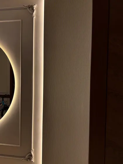 A detail shot of the corner of the backlit mirror, showing the intricate molding and the soft glow of the hidden LED strips.